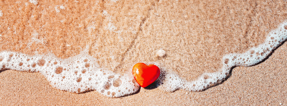 Romantic symbol of red heart on the sand beach