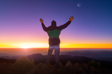 Fototapeta na wymiar A beautiful shot of a male raising his hands while facing the Pico de Orizaba Volcano in Mexico