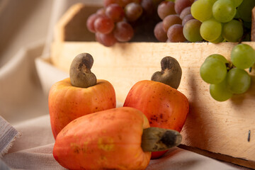 Grapes in a wooden box and cashews with fabrics in the background, low depth of field, selective focus.