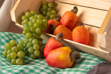 Grapes in a wooden box and cashews with fabrics in the background, low depth of field, selective focus.