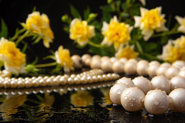 Pearl necklace and bouquet of roses with dew on wet surface, selective focus.
