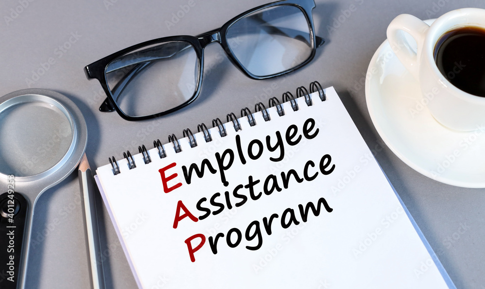 Poster employee assistance program, text on white notepad paper on a gray background near a magnifying glas