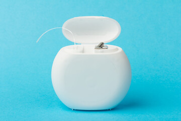 Dental floss container on blue background. Daily oral hygiene, teeth care and health. Cleaning...