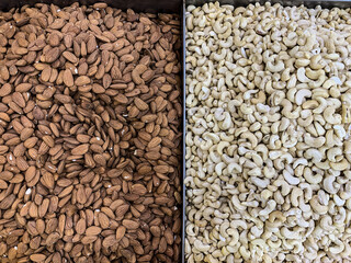 Brown the almonds and cashews in white trays on the market. Netanya, Israel