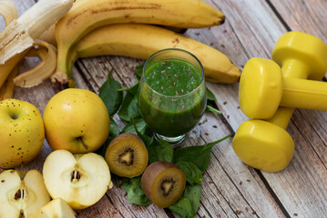 
A glass of kiwi, spinach and apple smoothie. Health drink. Apples, flax seeds, spinach, kiwi, bananas lie nearby.