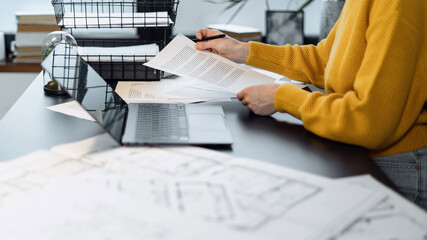 Woman working at office with blueprint and documents