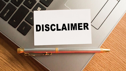 Notepad with the text DISCLAIMER is on the laptop keyboard. Minimal work space. Business concept.