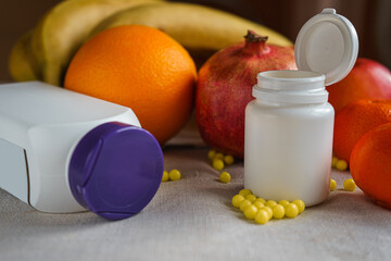 Bottles with vitamins lie on a gray canvas and on the background of fresh fruit, focus from the side