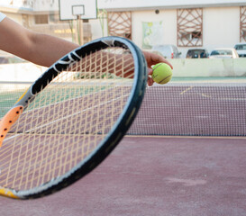 A racket and ball for playing tennis close up on the background of a tennis court.