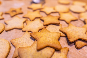 Homemade gingerbread cookies (stars) on baking paper and rustic wooden table
