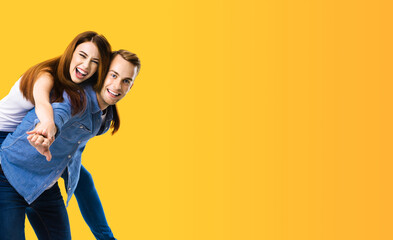 Smiling amorous funny couple. Portrait image of standing piggy back ride models in love studio...