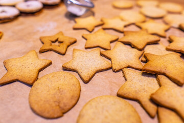 Homemade gingerbread cookies (stars) on baking paper and rustic wooden table
