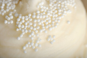 Close up of white sprinkles on vanilla icing for dessert macro view.