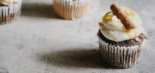 Sweet cupcakes with decorative icing for baked goods, copy space on texture background.