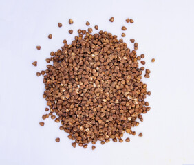 Brown buckwheat heap isolated on white background. Bio nutrition, natural food ingredient. Close up top view. Free space for copy
