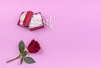 gift box with pills and rose on pink background