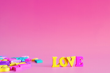 word love on a pink pastel background consists of colorful wooden letters in an abc alphabet block, copy space for your ad text. English learning concept