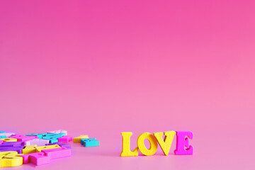 word love on a pink pastel background consists of colorful wooden letters in an abc alphabet block,...