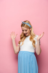 surprised blonde young pregnant woman on pink background.