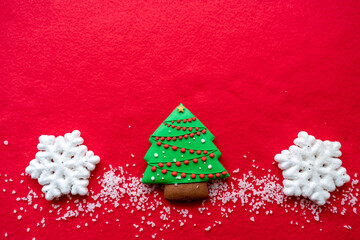  Top view of a decorated Christmas tree with snow and snowflakes on a red background. Minimal new...