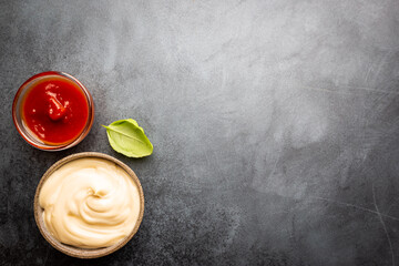 Classic set of sauces, American yellow mustard, ketchup, barbecue sauce, mayonnaise on black stone...