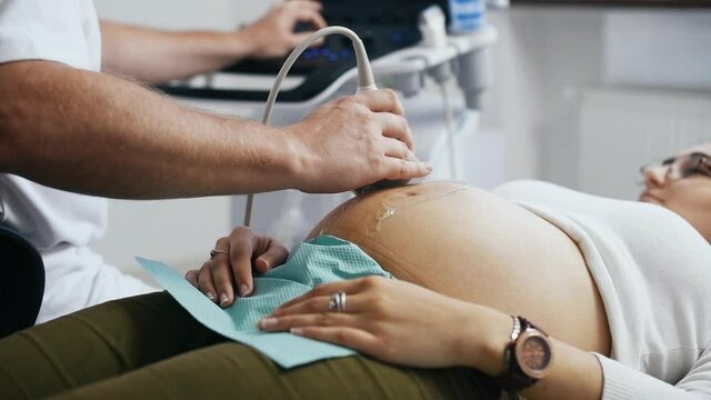 Male doctor does ultrasound for a pregnant woman in the clinic.
