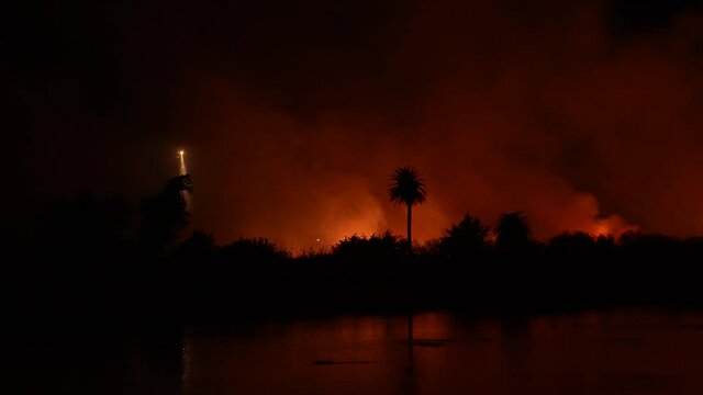 People watch massive fire burning at river bottom in Ventura, CA. 