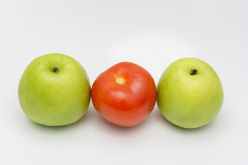 A red tomato placed between two green apple showcasing diversity with white back ground
