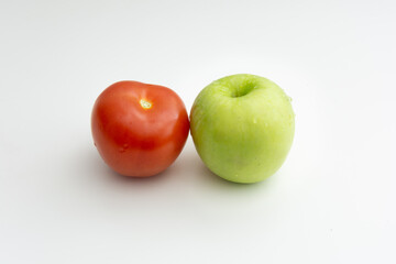 A red tomato placed next to  green apple showcasing diversity and friendship with white back ground