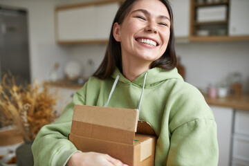 Adorable emotional young female in comfy clothes having excited facial expression, smiling happily,...