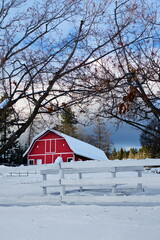 A red barn surrounded by trees in a snow-covered winter landscape.
