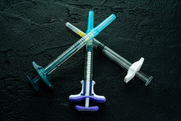  cosmetology  injections. Plastic syringe on black background. Medical syringe. botox filler cosmetic. beautician professional concept