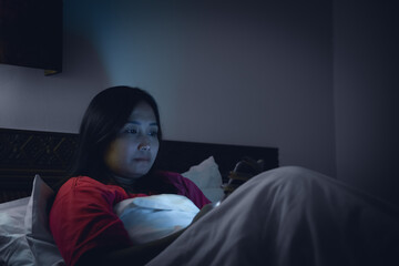 Asian woman playing game on smartphone in the bed at night,Thailand people,Addict social media