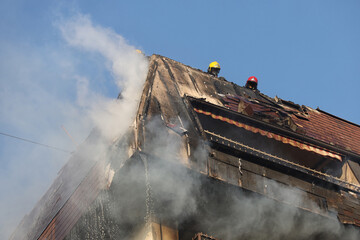 Firefighters On Flaming building Roof