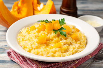 Pumpkin risotto with parmesan cheese and parsley in plate on wooden background