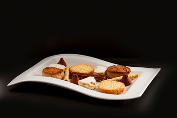 Assortment of Spanish Christmas sweets consisting of nougat, polvorones, chocolate bonbons, butter cookies, wafer eclairs and chocolate nougat.