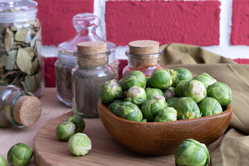 ripe Brussels sprouts lies in a wooden bowl next to spices