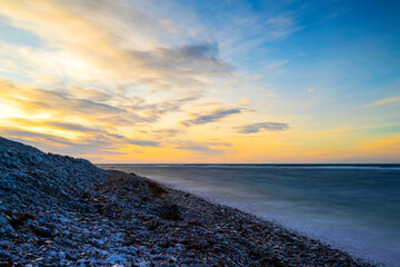 Sunset over a cold deep blue Baltic Sea with a cobblestone beach in the foreground at island of Gotland in Sweden