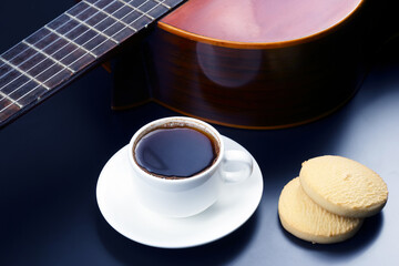 white cup with coffee and biscuits in the background acoustic guitar