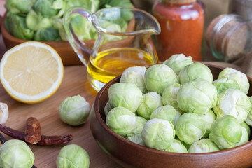 various spices, butter, sliced lemon on a board, peeled and washed Brussels sprouts lie in a wooden bowl