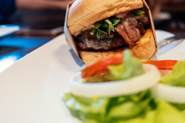 Juicy beef burger with bacon, vegetables and gluten free bun. Selective focus. Street food concept.