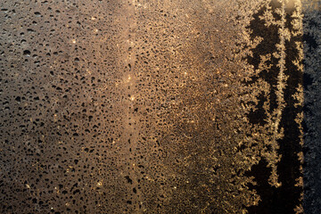 A frozen window thaws in the sunlight. Texture