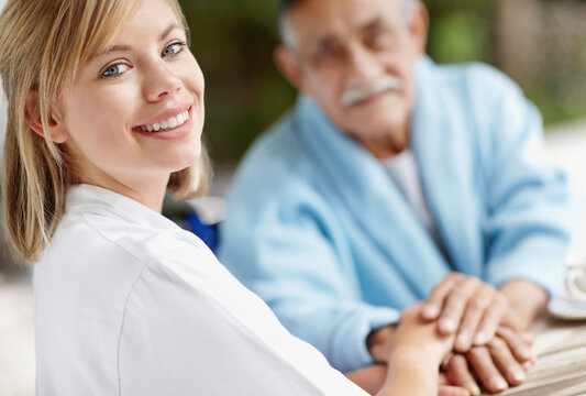 Nurse and senior man holding hands