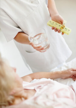 Nurse giving pill to senior woman