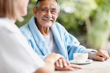 Senior man sitting at table with nurse