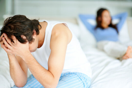 Frustrated man sitting on edge of bed