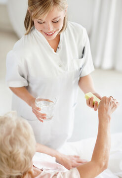 Nurse giving pill to senior woman