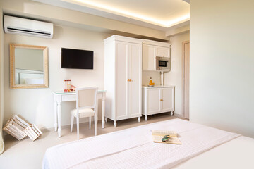 White elegant interior of small studio apartment room with classic style design wooden panel furniture in modern hotel flat.
