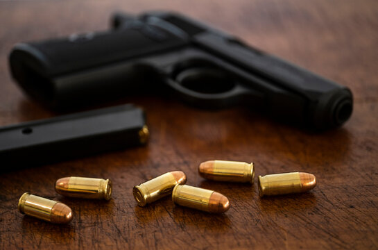 Gold bullets and pistol on wooden surface