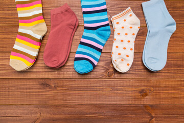 multicolored new socks in different sizes stacked on a wooden background. clothes for women